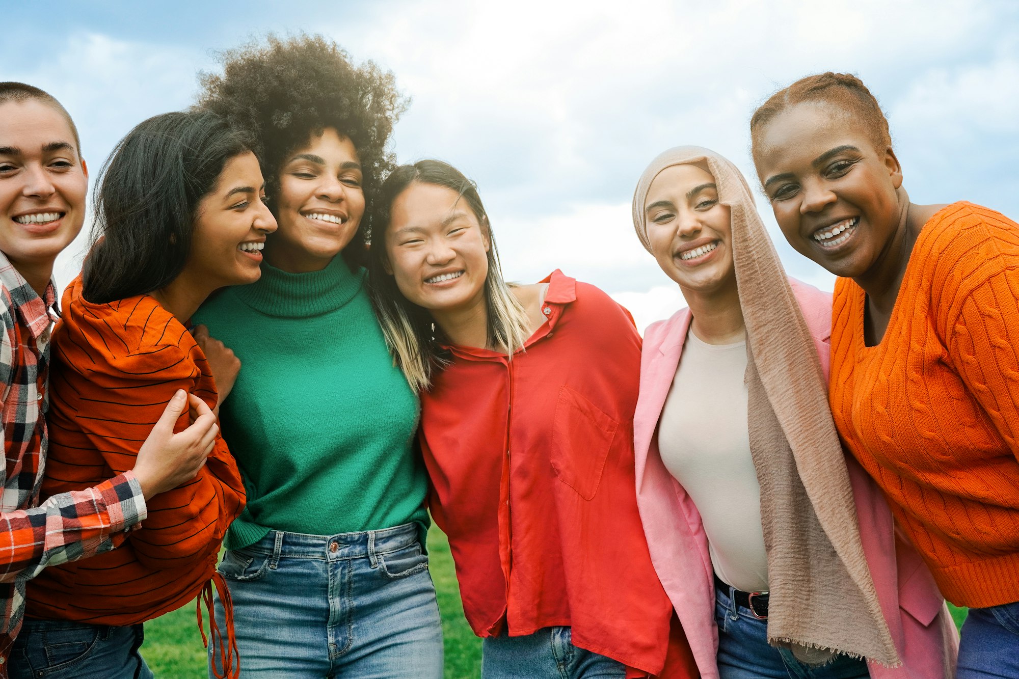 Multiracial group women friends hugging each other outdoors at park city - International people